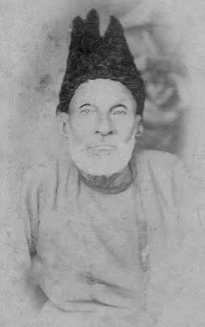 Photograph of Mirza Ghalib in his later years, wearing a tall dark cap